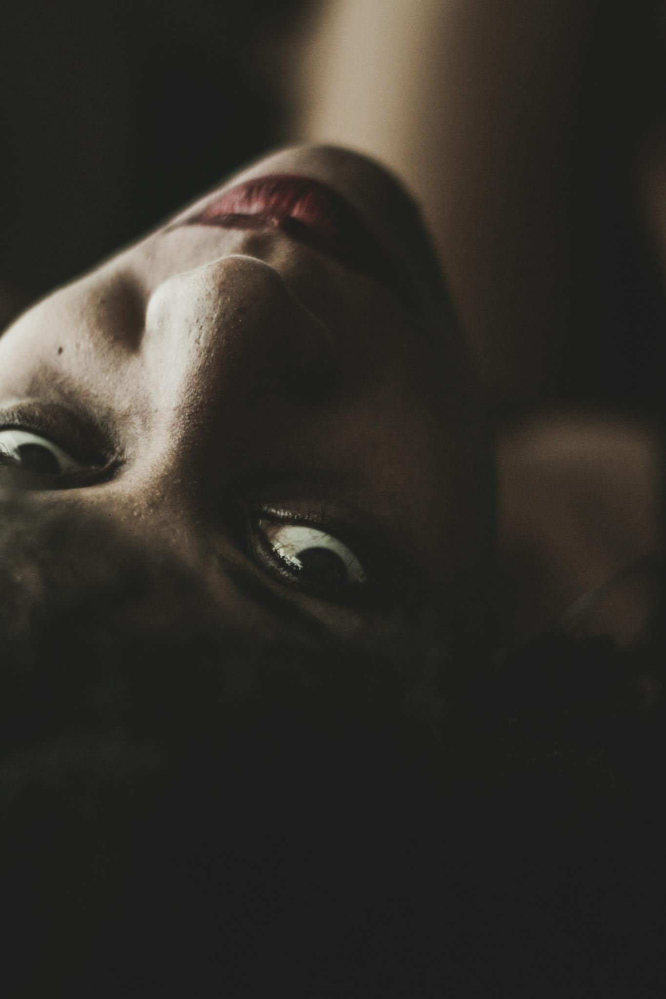 Evocative close-up portrait of a woman with intense gaze and dark, moody lighting.